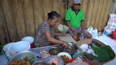 UBUD, BALI, INDONEZYA - 27 Nisan 2019: Endonezyalı fakir insanlar, Endonezya 'nın Bali adasındaki Ubud köyündeki sabah pazarında sağlıklı yiyecek satıyor ve satın alıyorlar. Sabah meyve ve sebze pazarı