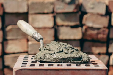Çimento karışımı ya da harç. İnşaat alanındaki kırmızı tuğlada çimento tozu ve mala yakın.