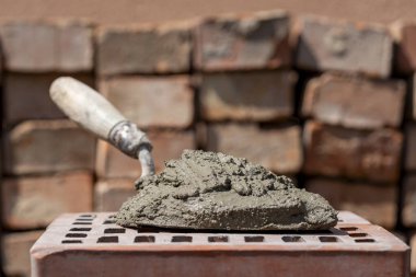 Çimento karışımı ya da harç. İnşaat alanındaki kırmızı tuğlada çimento tozu ve mala yakın.