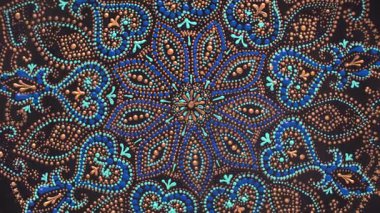 Dekoratif seramik tabak, siyah, mavi ve altın renkli, arka planda boyalı, yakın plan, üst manzara, döndürme. Akrilik boyalarla boyanmış dekoratif porselen tabaka, el işi, nokta boyası.