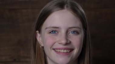 Güzel mutlu bir kızın portresi. Sarı saçlı ve çilli. Kameraya bakıyor ve büyüleyici bir şekilde gülümsüyor.