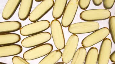 Omega 3 ve beyaz arka planda D vitamini içeren balık yağı kapsülleri, yakın plan, dönüyor. Jelatin kapsüllerde altın balık yağı