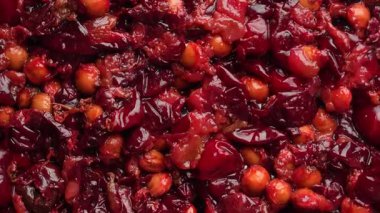 Red cherry pits and pulp after squeezing out the juice as a background, close up. Texture of cherry kernels. Top view, rotates