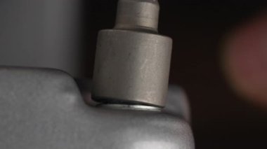 We unscrew the metal nut from the bolts thread in the steel workpiece, close up