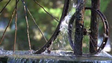 Güneşli bir günde Batumi şehrinde su sıçrayan güneş ışığına karşı güzel bir çeşme ve bisiklet tekerleği, Georgia. Ağır çekim, yakın çekim.