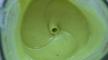 Meyveler sağlıklı yeşil bir meyve püresi ile harmanlanmış. Taze muz ve avokado kokteyli. Sağlıklı beslenme ve yaşam tarzı kavramı. Yakın çekim, yavaş çekim, üst görünüm