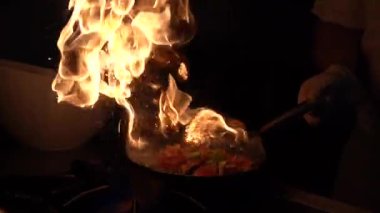 Şef, sebzeleri kızartıp tavaya atıyor. Türkiye 'deki sokak kafesinde sebzeli kızartma tavalarının büyük bir alevle kavruluşunun yavaş çekim görüntüsü. Mutfakta kızarmış sebze pişireceğim.