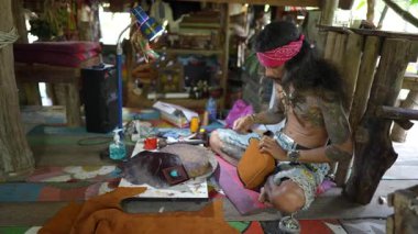 Koh Phangan, Tayland - Şubat, 06, 2022: Taylandlı zanaatkar Koh Phangan, Tayland 'da bir sokak pazarında deri çantalar dikiyor.