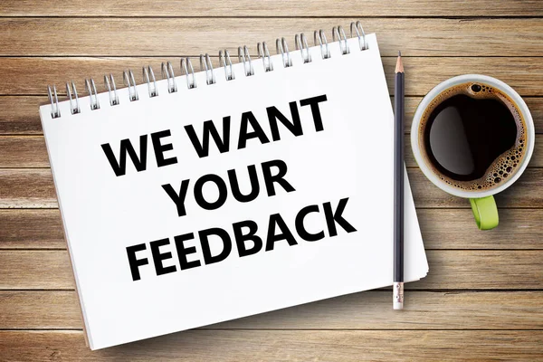 We Want Your Feedback. Text on notebook on office desk workplace background. Business strategy concept.Notepad or notebook with pencil on brown wood table
