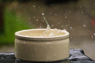 rain is falling in a small white barrel full of water in the garden