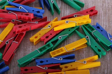 Ahşap bir masanın üzerinde duran renkli mandalların yakın çekimi.