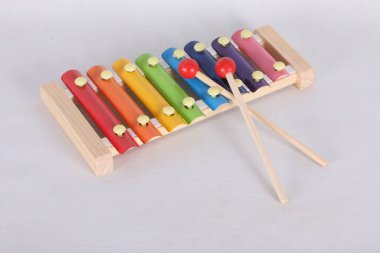 close-up of a small wooden xylophone with colorful bars and 2 wooden mallets with red balls clipart