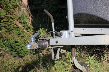 close-up of a trailer hitch of a trailer standing in green grass clipart