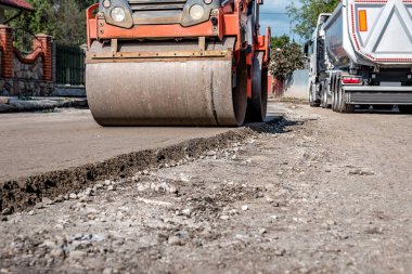 The process of laying a pavement of several layers of asphalt on a sand base. Heavy road rolls machinery. Industrial transportation theme