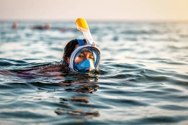 Young woman swimming in the sea with modern snorkeling gear. Full face snorkeling mask. Tropical sea sport activity. Summer vacation in exotic island