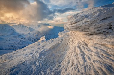 Frosty pattern on a rock in winter mountain at sunset. Frozen snow covered land. Beautiful landscape. Strange snow formation at a mountains peak
