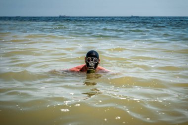 Denizde gaz maskeli bir adam. Çevre kirliliği teması
