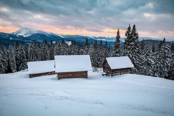 Amazing landscape with abandoned cabins in winter Carpathian mountains at sunset