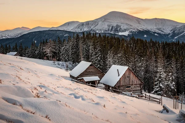 Beautiful winter landscape with cabins at amazing sunset in the snowy Carpathian mountains