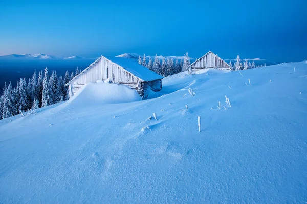 Landscape with beautiful sunrise or sunset and cabins in winter Carpathian mountains