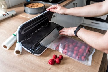 Woman use vacuum sealer packing machine for long-term storage of products. Vacuum strawberries packaging for long-term storage. clipart