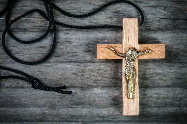 冬青木基督教的十字架与黑色的绳子上木制背景 — 图库照片