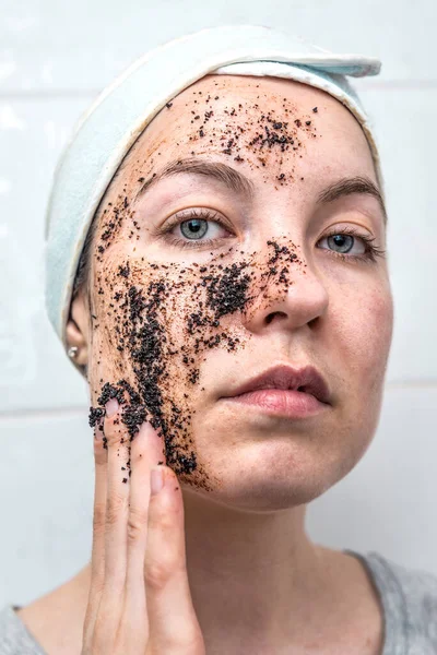 Woman uses coffee scrub for cleaning face skin