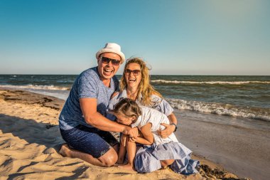 Fynny mutlu bir aile gün batımında kumsalda oynuyor.