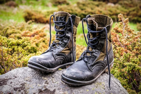 Military black leather hiking boots on the stone