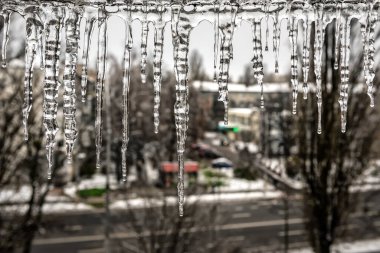 Evin çatısından sarkık buz saçakları sarkıyor. Kış kasabasının sokaklarında büyük buz sarkıtları. Kış zamanı