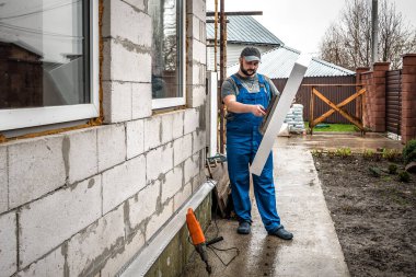 İşçi, duvarda yapışkan köpük tutuyor. Yalıtım yapmak enerji tasarrufu sağlar. Sahne Efendisi