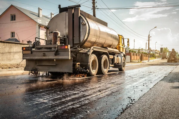 一辆装有油罐的卡车把沥青倒在第一层沥青上 工业主题 免版税图库图片