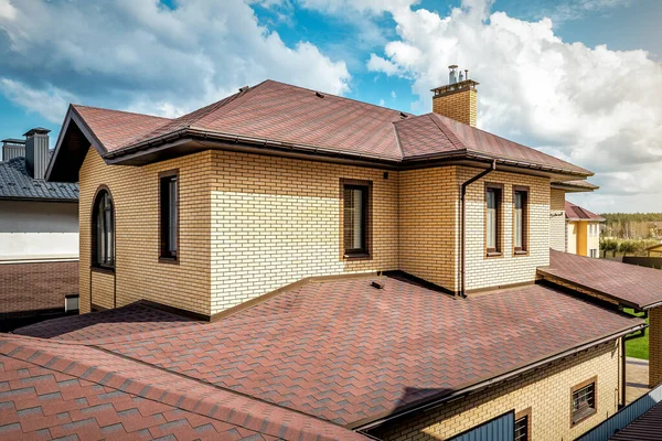 Modernes Hausdach Mit Neuen Braunen Dachschindeln Unter Wolkenverhangenem Himmel lizenzfreie Stockbilder