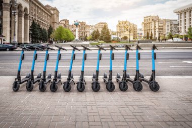 Şehir sokaklarında kiralık elektrikli scooter 'lar. Çevre dostu elektrikli scooter kiralama servisi. Şehir manzarası