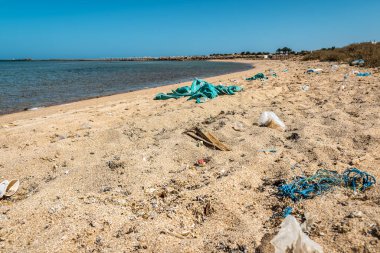 Kayın kumunun üzerindeki farklı çöpler. Çevre kirliliği teması