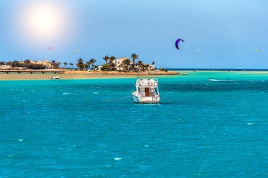View of a yacht and a beautiful island and many kite surfers on the Red Sea in Egypt. Summer vacation theme clipart