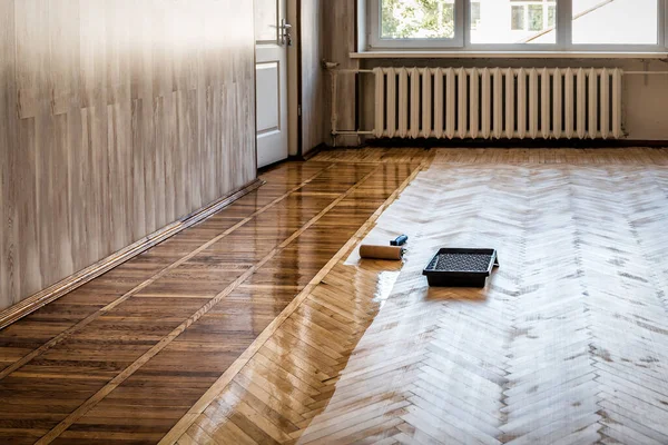 Lacquering wood floors. A roller to coating floors. Varnishing lacquering parquet floor by paint roller - second layer. Home renovation parquet. Industrial theme