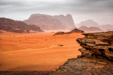 Kızıl Çöl 'de Mars manzaralı Wadi Rum kervanı. Yağmurlu bulutlar