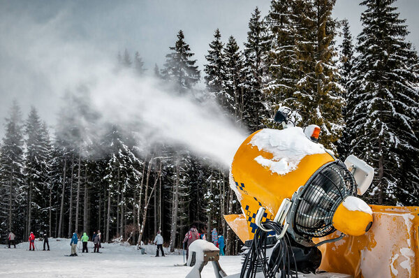 Professional artificial snow machine cannon making snowflakes from water at ski resort