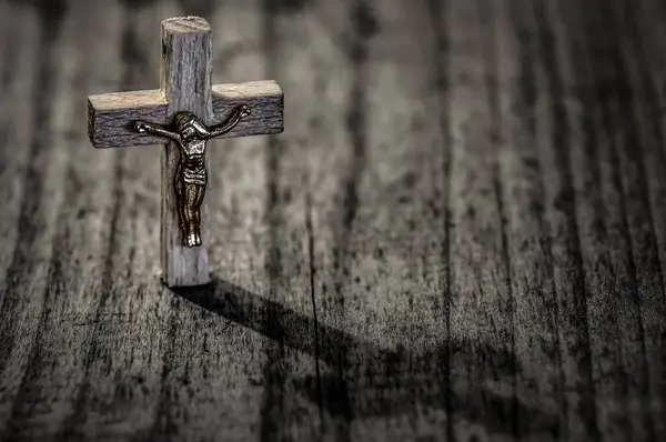 Wooden cross with crucifix and shadow om wooden background