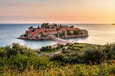 Karadağ 'ın Adriyatik kıyısında gün batımında Budva yakınlarındaki küçük bir ada olan Sveti Stefan' ın görüntüsü. Seyahat ve tatil teması