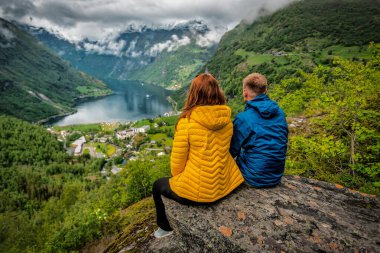 Norveç 'teki Fiyort' ta oturan mavi ve sarı elbiseli çift. Seyahat ve tatil teması