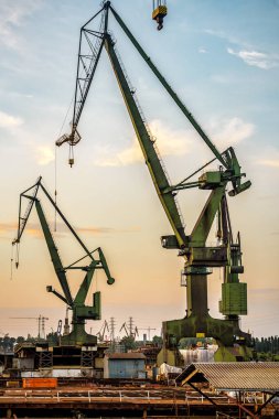 Gün batımında deniz terminalinde endüstriyel vinçler. Sanayi teması