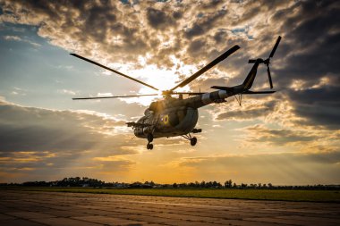 Askeri helikopter gün batımında havalanıyor.
