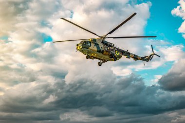 Askeri büyük helikopter MI8 hava bulutlu havada gün batımında uçuyor.