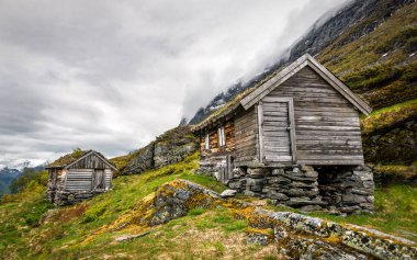 Norveç 'in vahşi dağlarında taş bodrum katında çimen çatılı ahşap kulübeler.