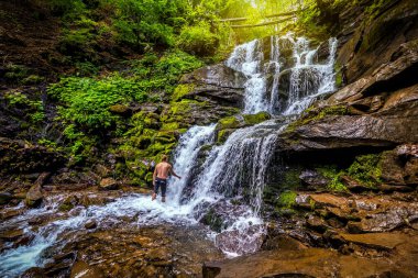 Vahşi ormandaki güzel şelalenin altındaki adam. Seyahat ve tatil teması