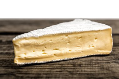 Lezzetli brie peynirinin üçgeni beyaz arka plandaki eski tahta üzerinde.