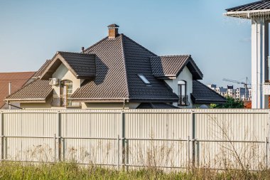 Mavi gökyüzünün altındaki terk edilmiş evin kahverengi çatısı.