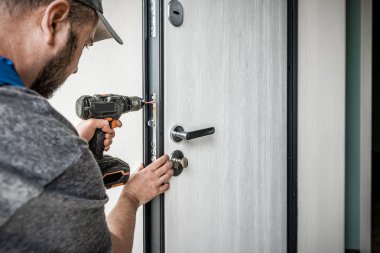 Profesyonel çilingir elektrikli tornavidayla giriş kapısını tamir ediyor. Sanayi teması